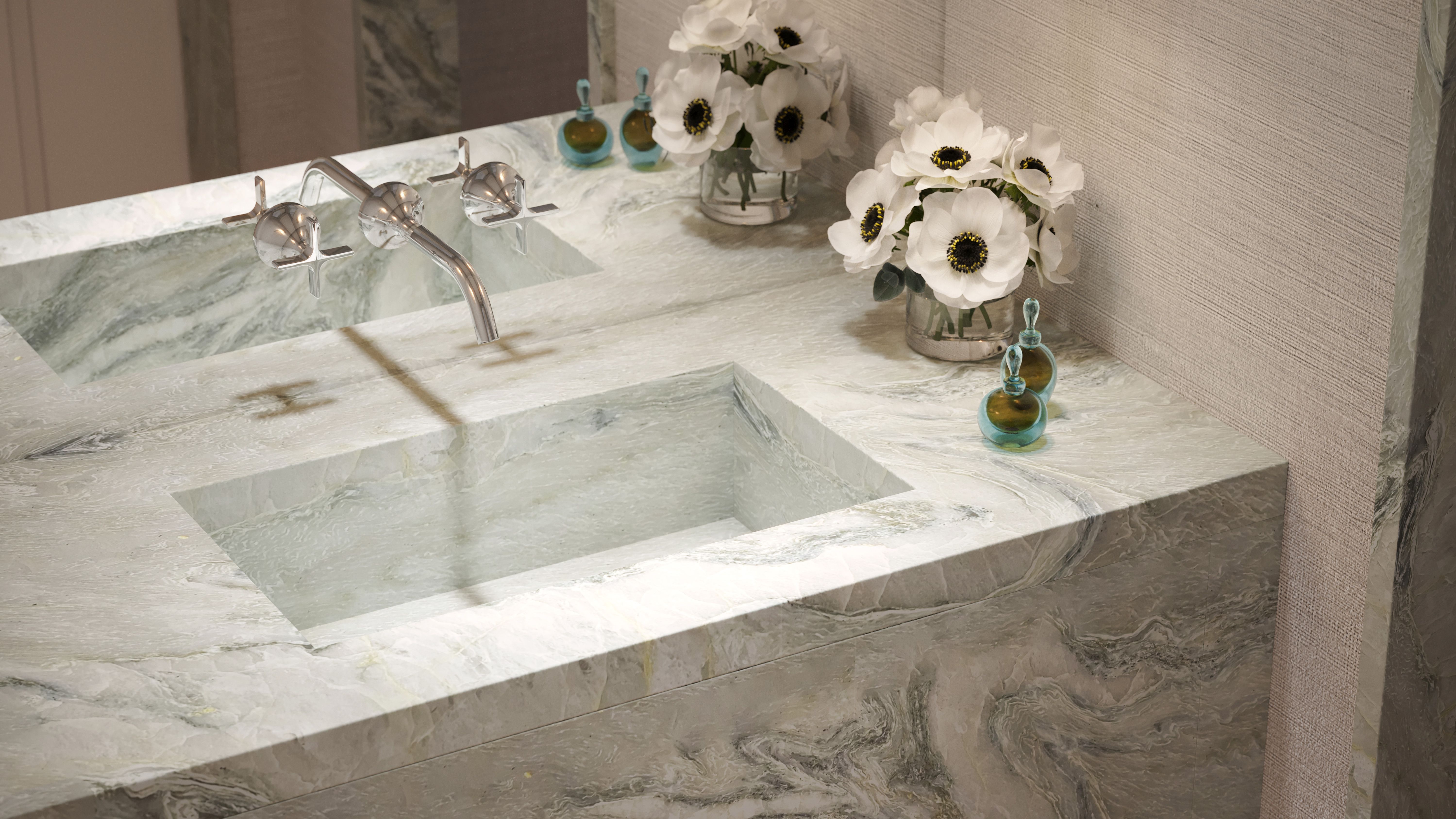 Powder rooms feature vanities clad in slabs of Maya Quartzite with custom integral sinks and Dornbracht Vaia plumbing fittings in polished nickel