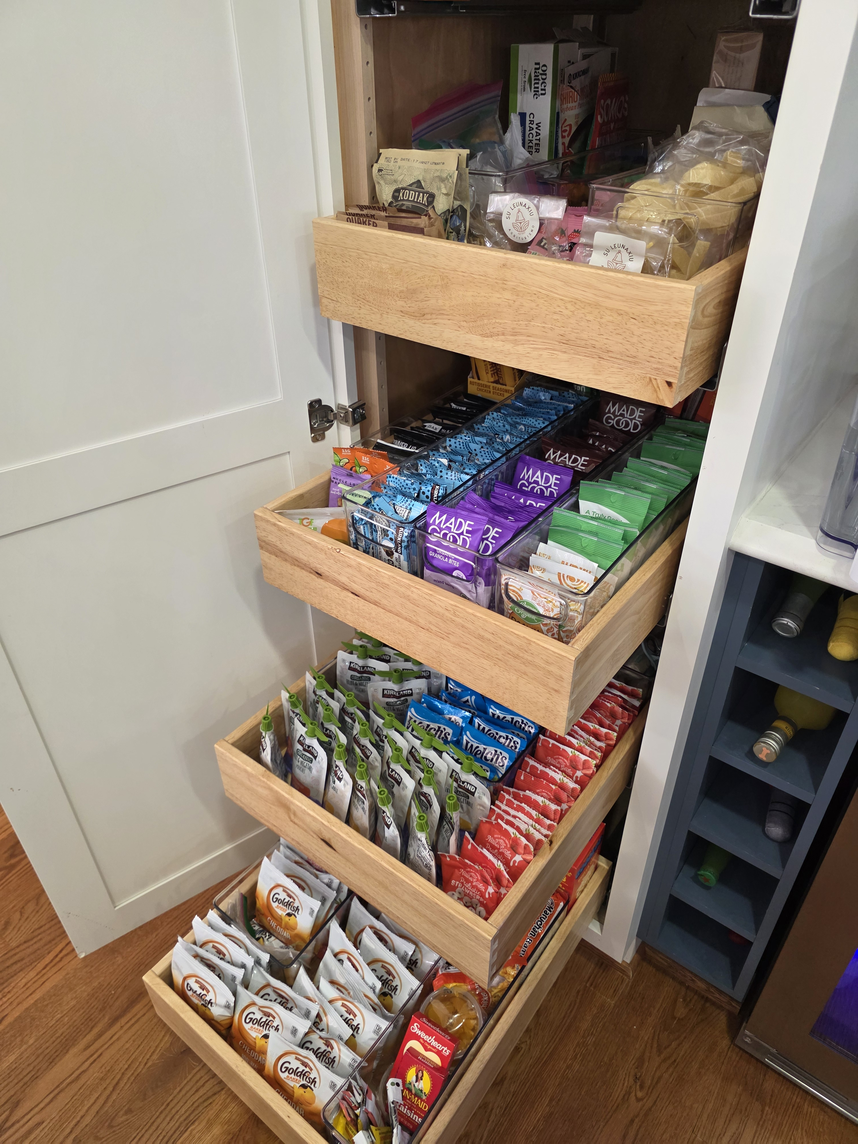 Pullout pantry with organized snacks and clear bins as dividers.