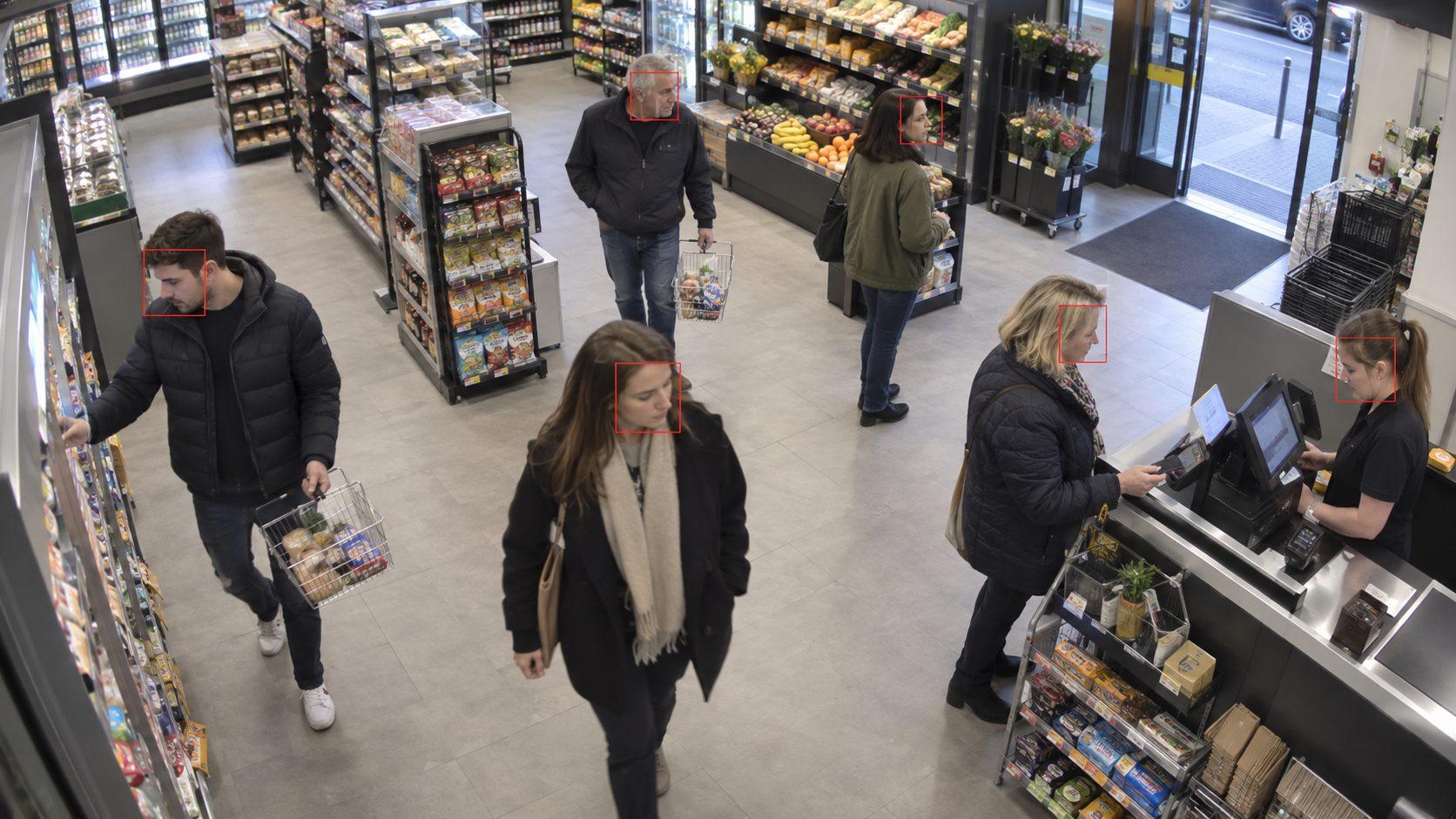 A shop interior seen from a Spotlight camera, with the system drawing a box around each person's face