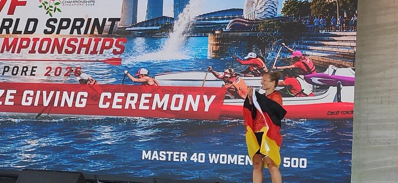 Christiane Pape mit Deutschlandflagge auf der Bühne der Siegerehrung in Singapur.