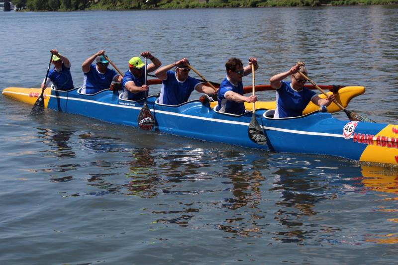 Seitenansicht des blau-gelben FRVS-Sechsers: Alle sechs Paddlerinnen und Paddler setzen gleichzeitig das Paddel ein.