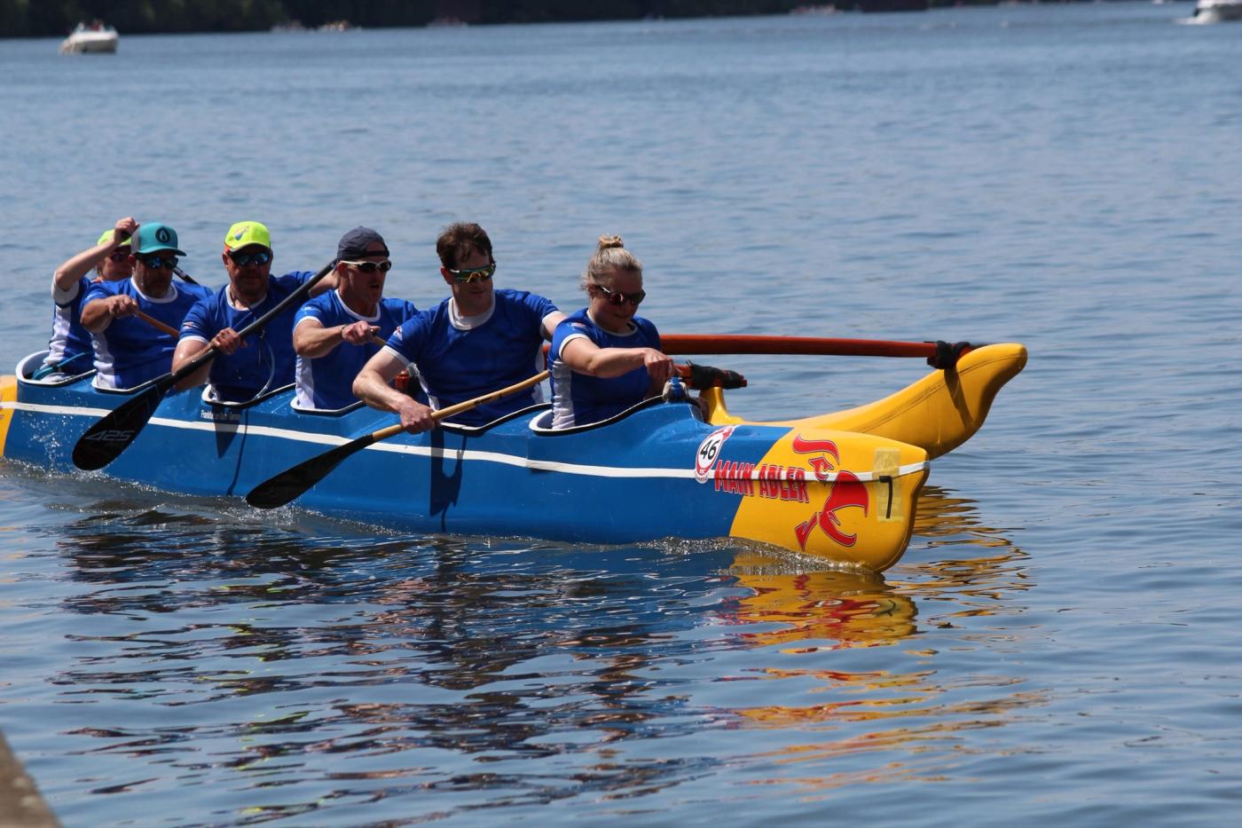Das blau-gelbe Outrigger-Sechserboot „Main Adler“ des FRVS mit sechs Paddlerinnen und Paddlern beim Main Metropolitan Cup 2026.