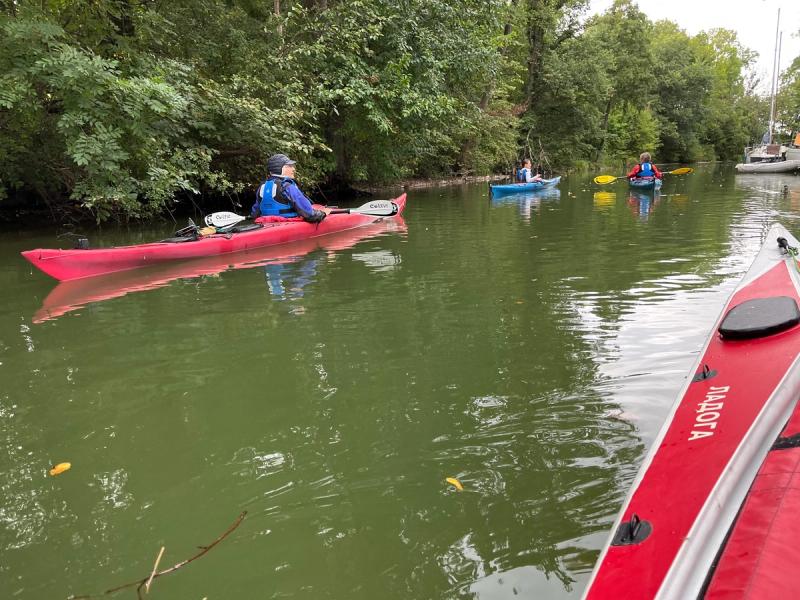 Paddler in einem roten Kajak auf einem grünen Kanal.