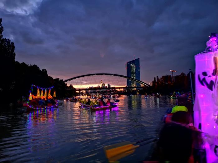 Schön iluminierte und geschmückte Boote in der Abenddämmerung vor der eindrucksvollen Skyline von Frankfurt