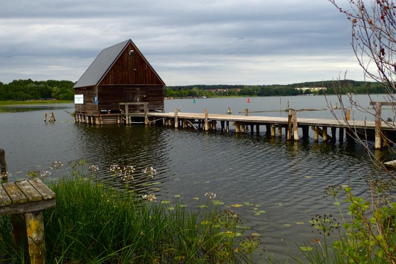 Holzbootshaus mit langem Steg an einem See.
