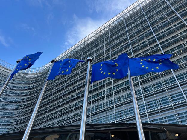 EU-flagg vaier foran en moderne glassbygning.