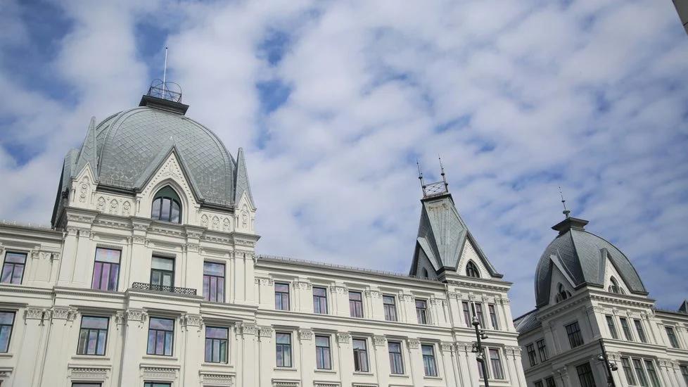 White ornate building with grey domes and spires against a cloudy sky.
