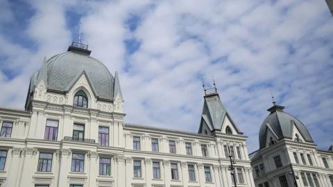 White ornate building with grey domes and spires against a cloudy sky.