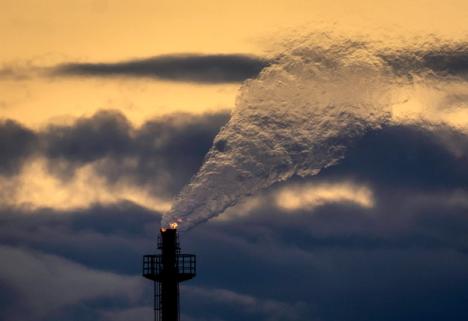 Et tårn slipper ut en stor sky av hvit røyk og flammer mot en mørk, oransjeopplyst himmel.