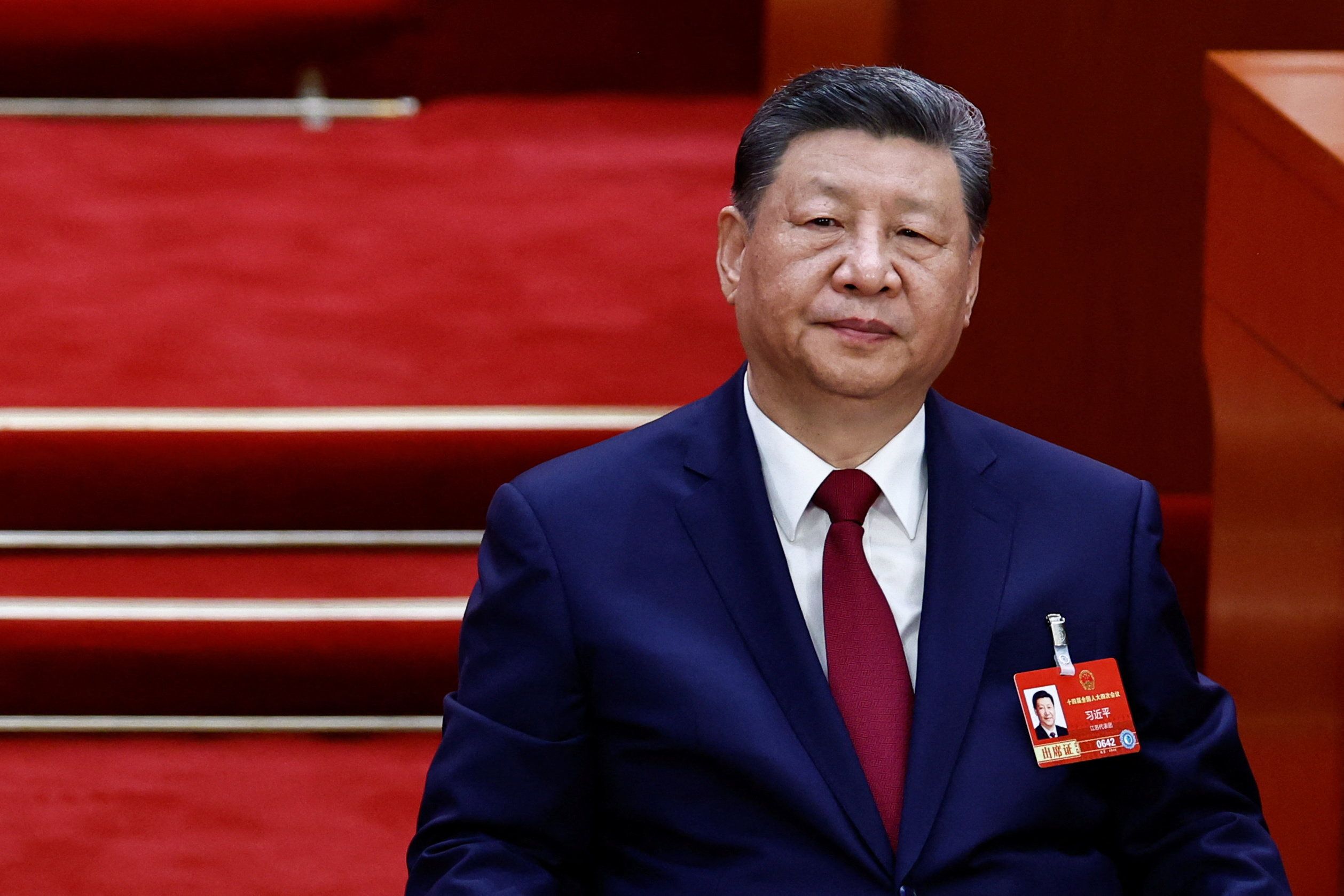 Xi Jinping iført en mørk dress og rød slips, som ser fremover.