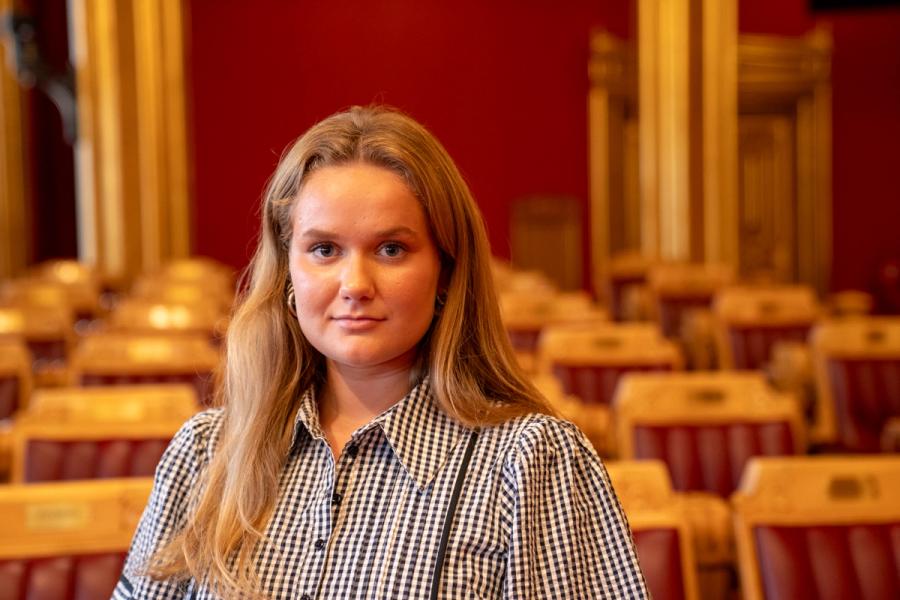 Bildet viser mdg-politiker, Frøya Sjursæter, stående i stortingssalen i rutete skjorte.