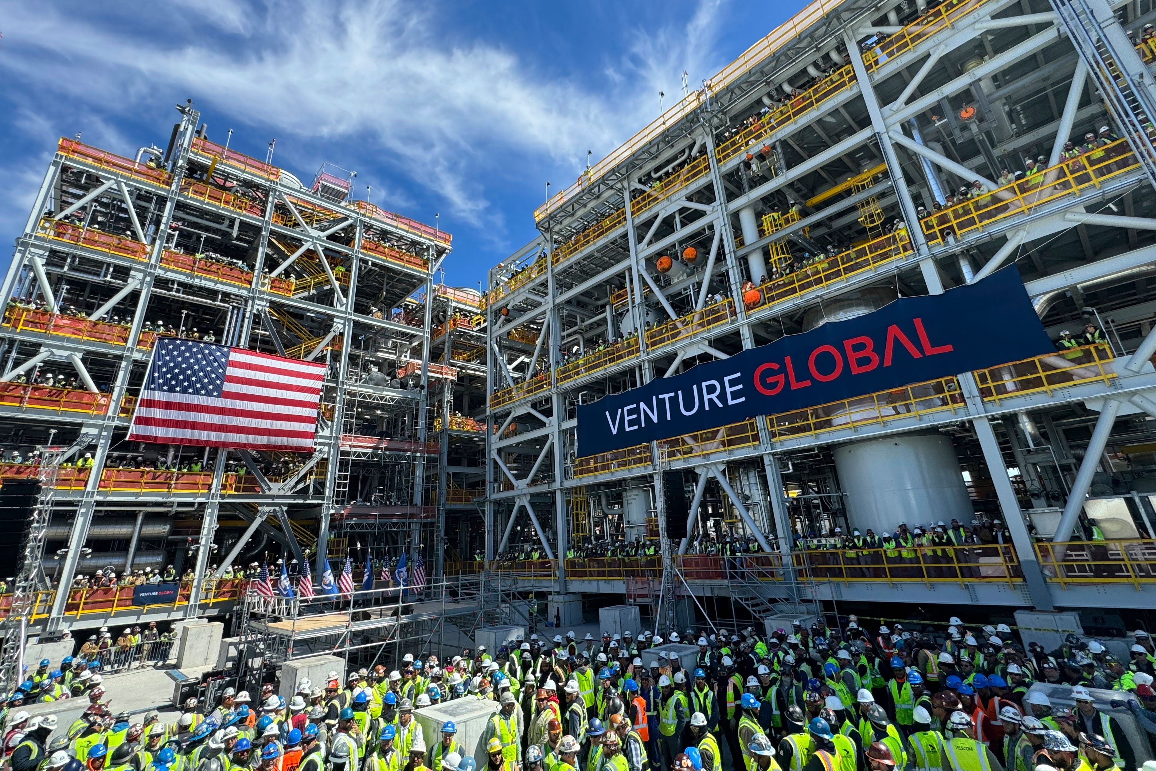 En folkemengde av arbeidere samler seg ved et stort industrianlegg som viser et amerikansk flagg og et banner med teksten «Venture Global».