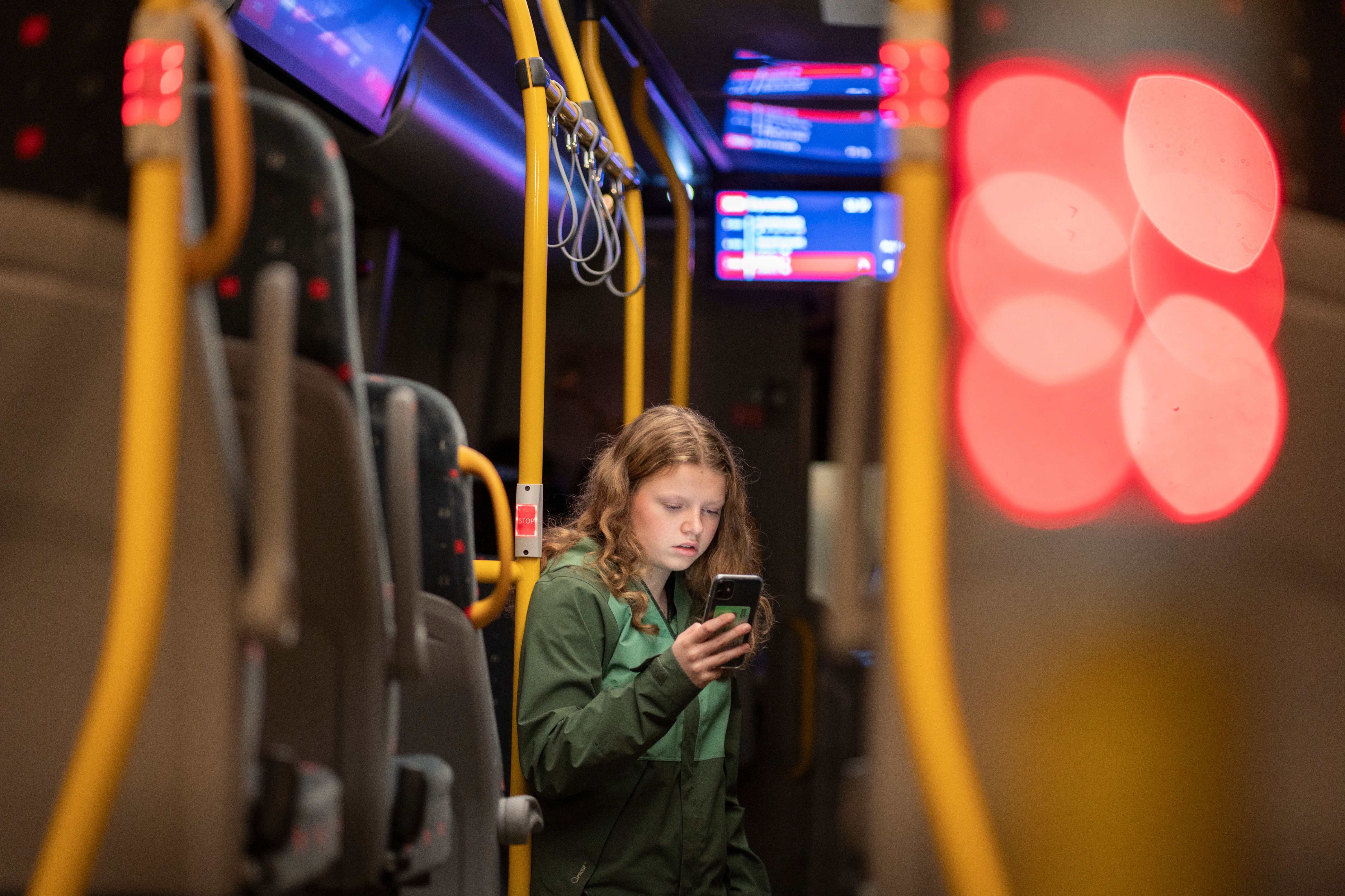 En ung jente ser på smarttelefonen sin inne i en buss.