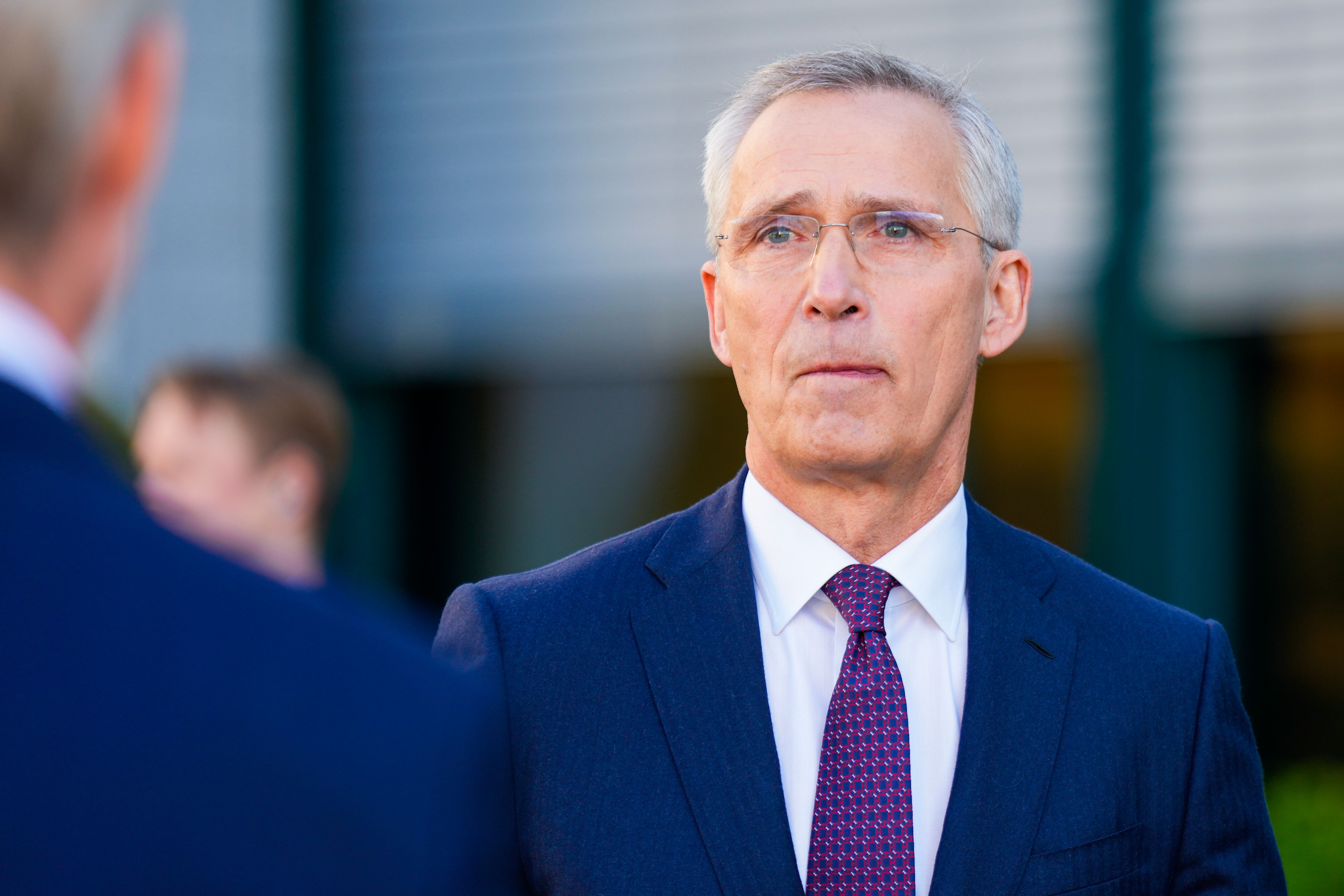 Jens Stoltenberg, iført en mørkeblå dress og briller, ser alvorlig mot venstre.