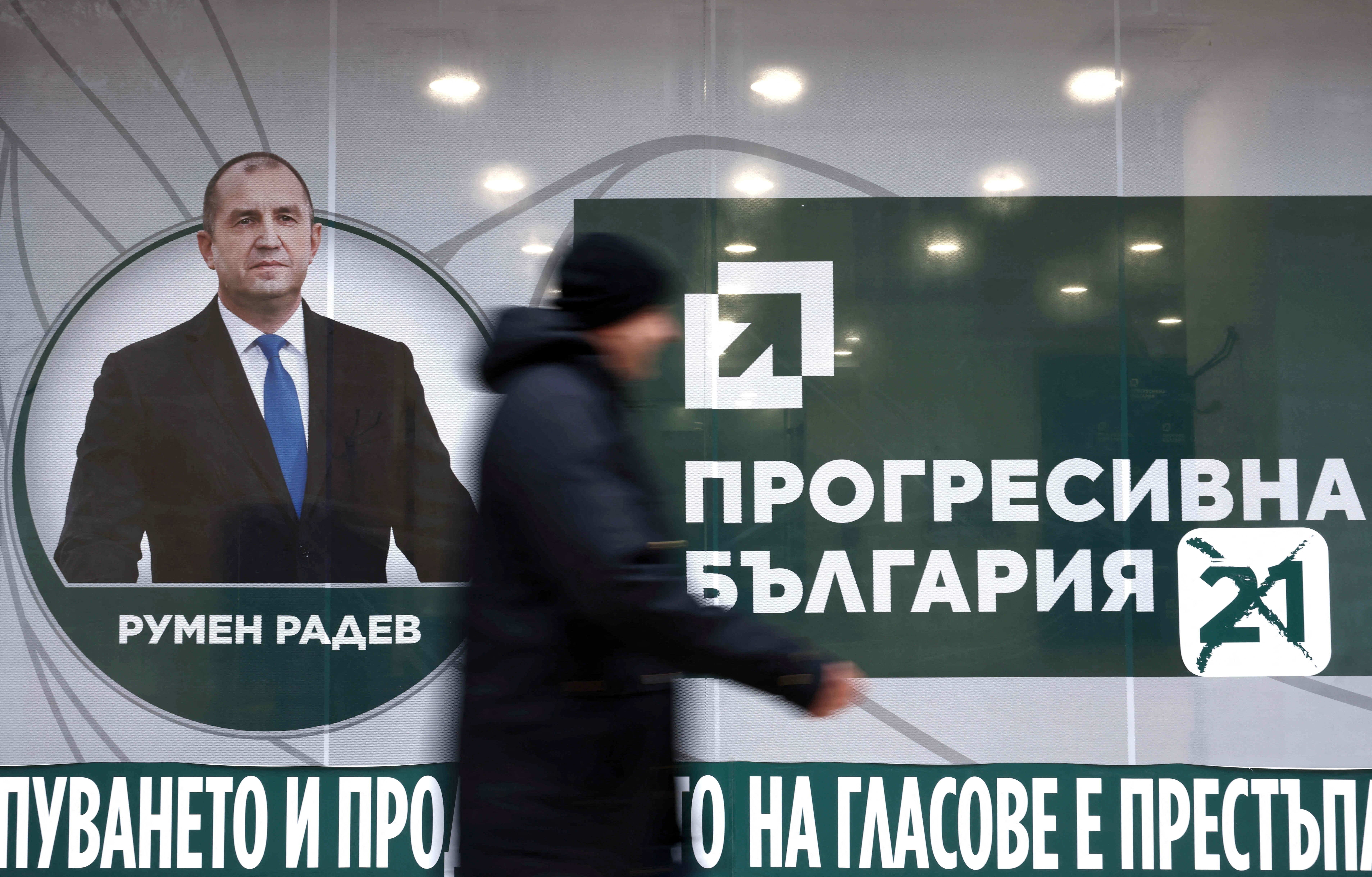 En uklar person går forbi en valgplakat for Rumen Radev og «Progressivt Bulgaria».
