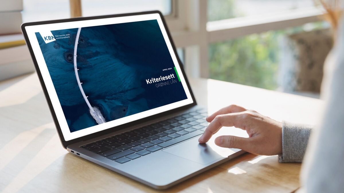 Person som bruker en bærbar datamaskin som viser et nettsted med overskriften "KriterieSett GMBH" på skjermen, i et solfylt kontormiljø.