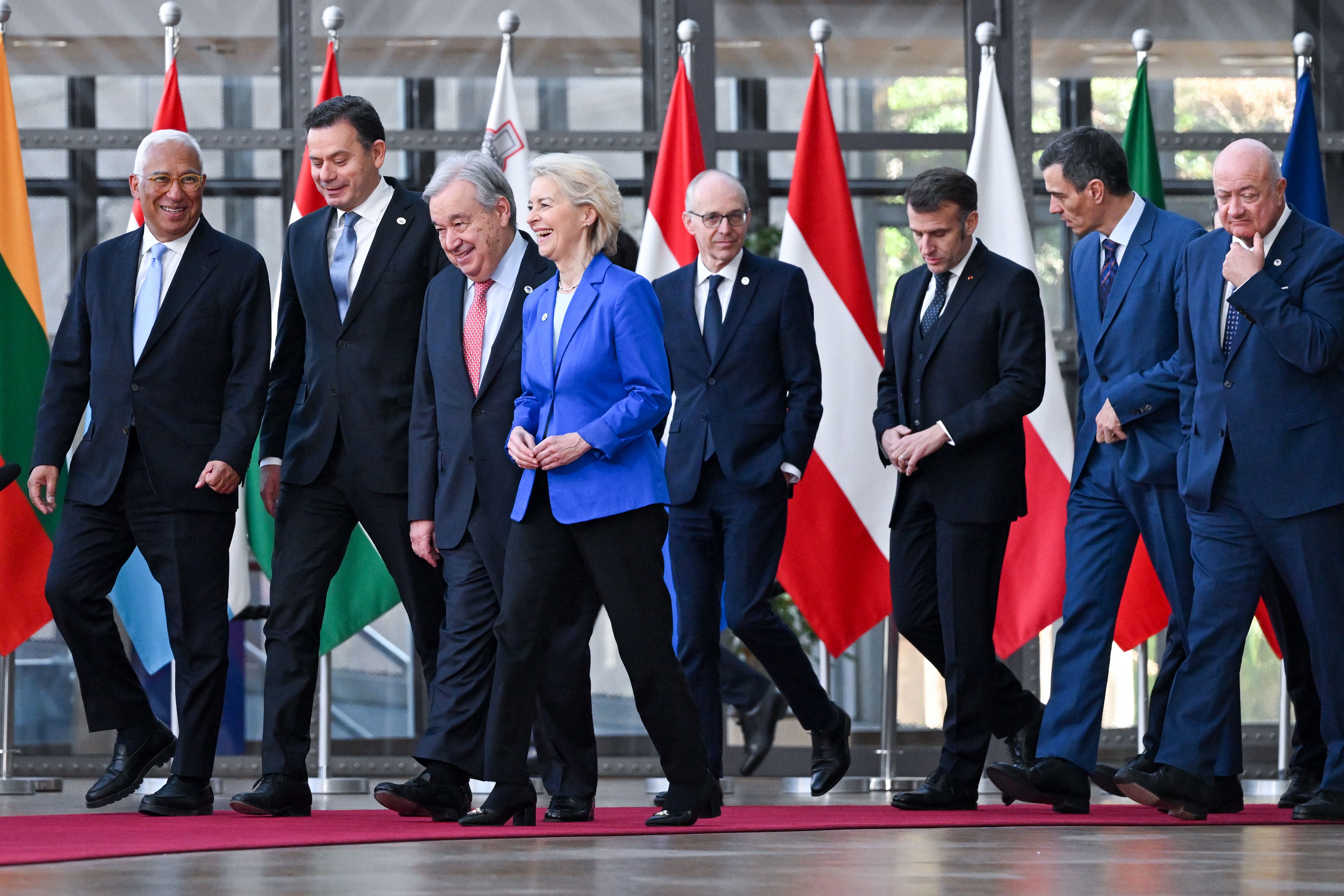 Ursula von der Leyen, António Guterres og andre verdensledere går på en rød løper med nasjonalflagg bak seg.
