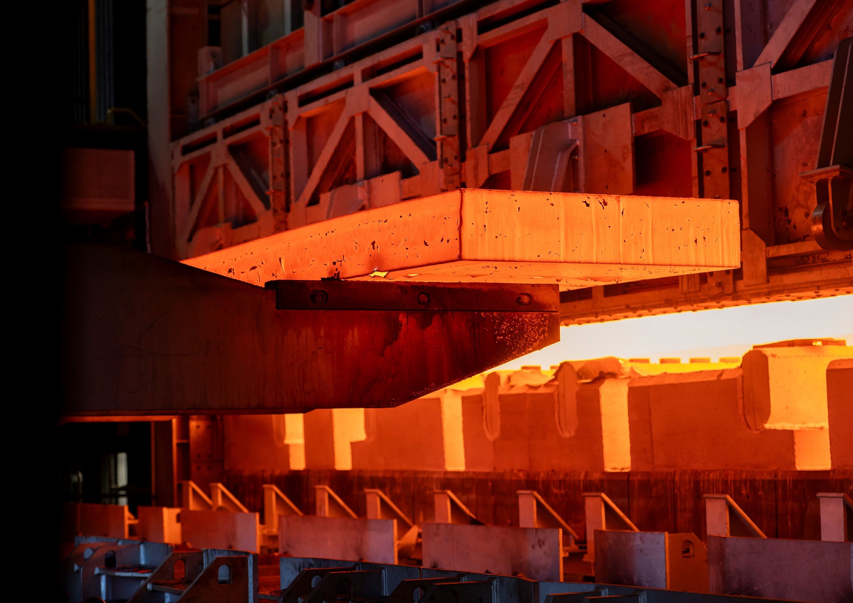 En stor, glødende varm metallplate som bearbeides i en industriforovn.