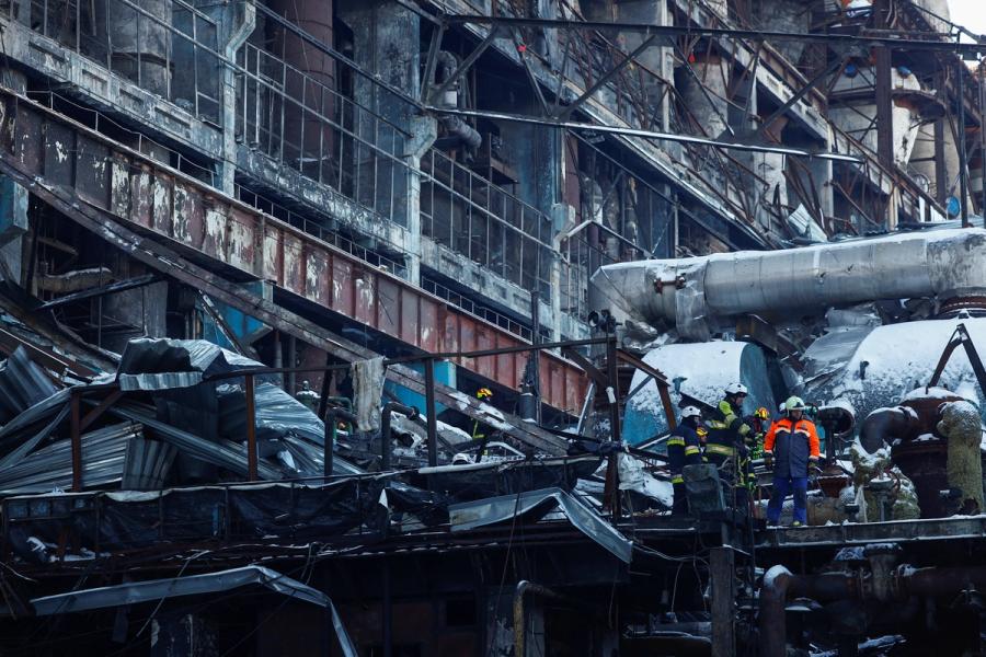 Arbeidere blant snødekte vrakrester av en sterkt skadet industribygning.
