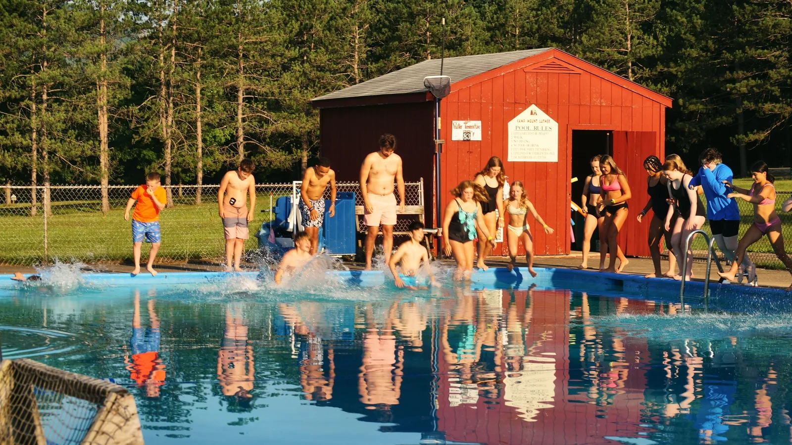 Campers jump into the camp pool on a sunny day