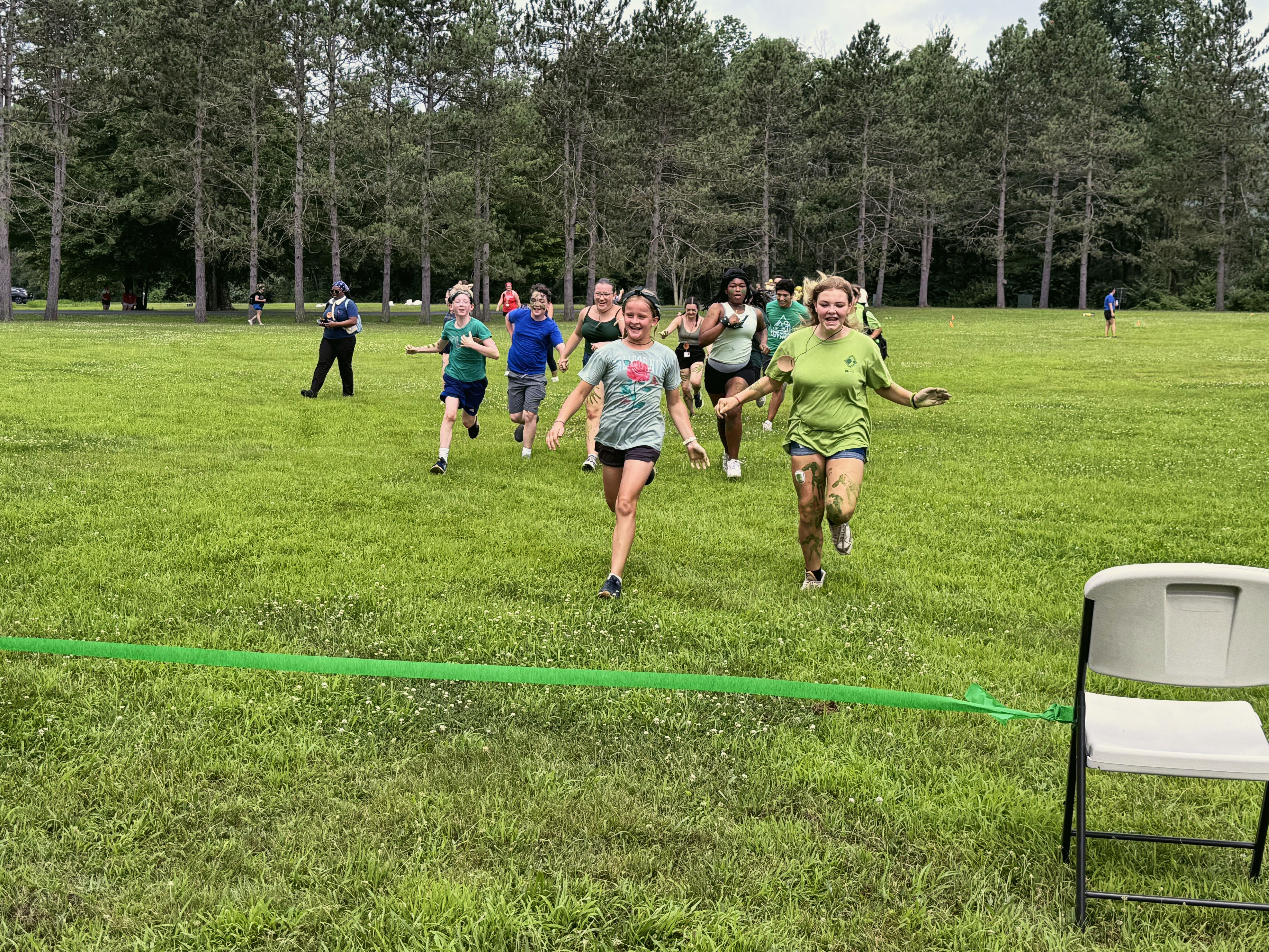 Young women run across a grassy field toward a green finish line