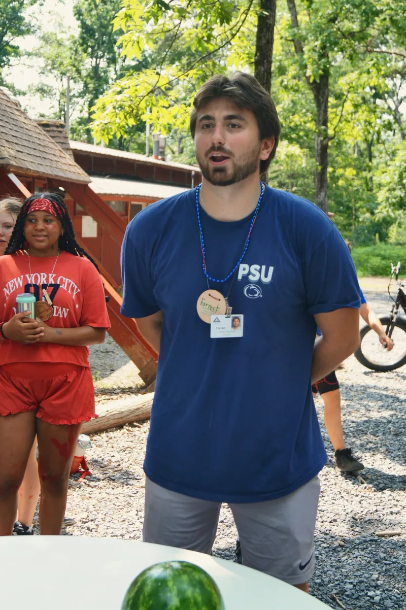A young counselor talks with a group of campers outside a cabin