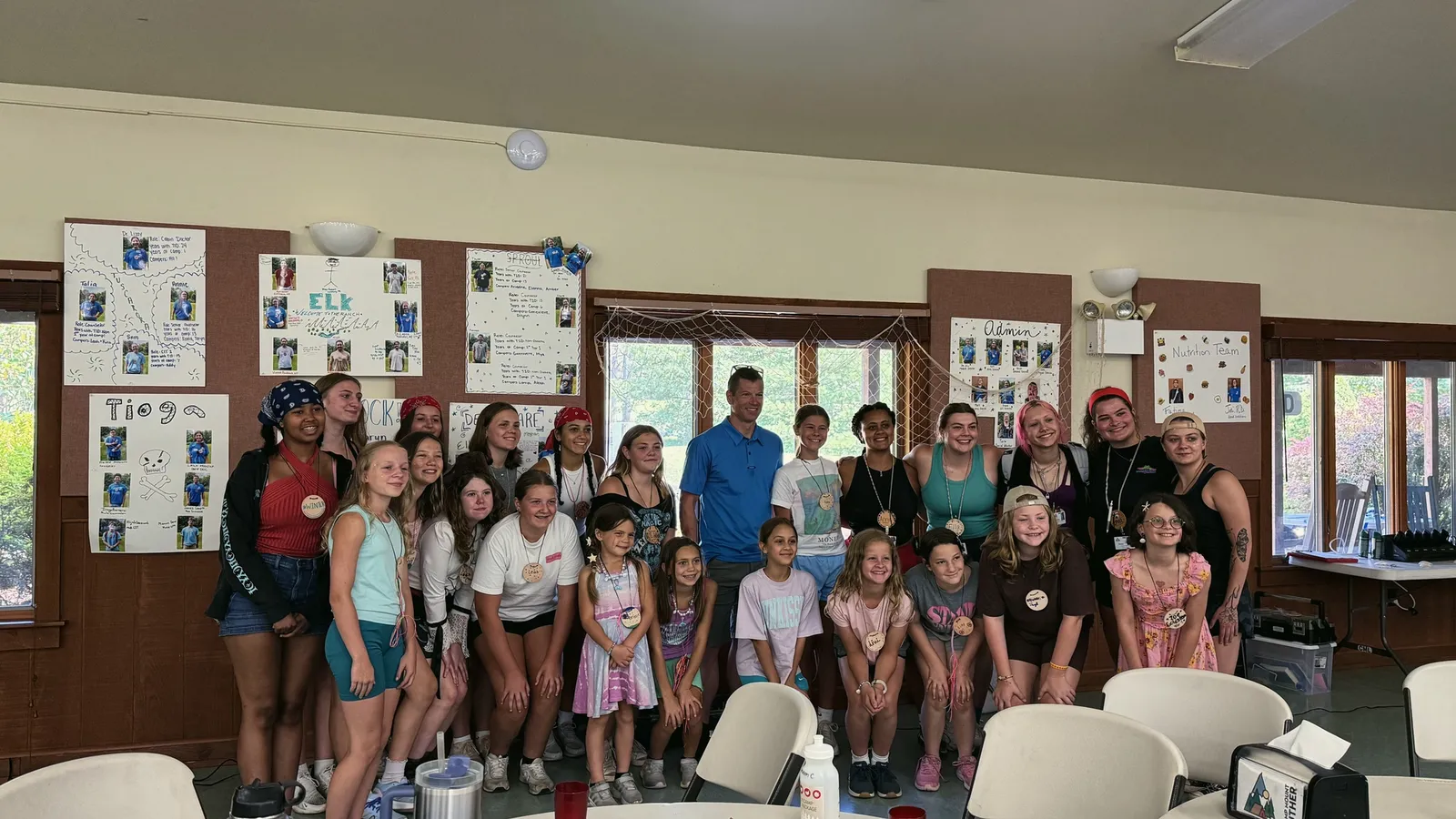 Children and adults stand together for a group photo indoors
