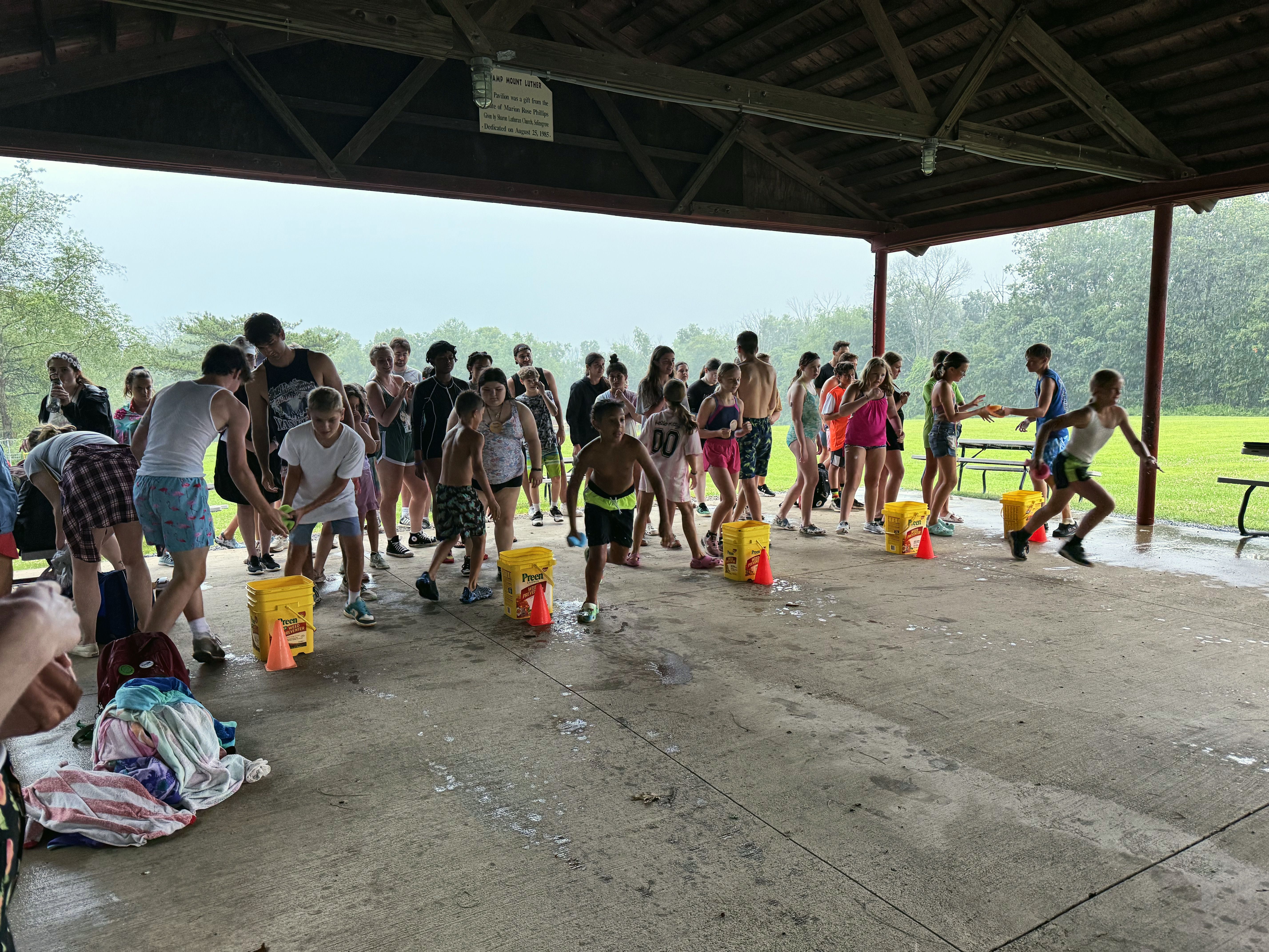 Campers run a water bucket relay race under the covered pavilion