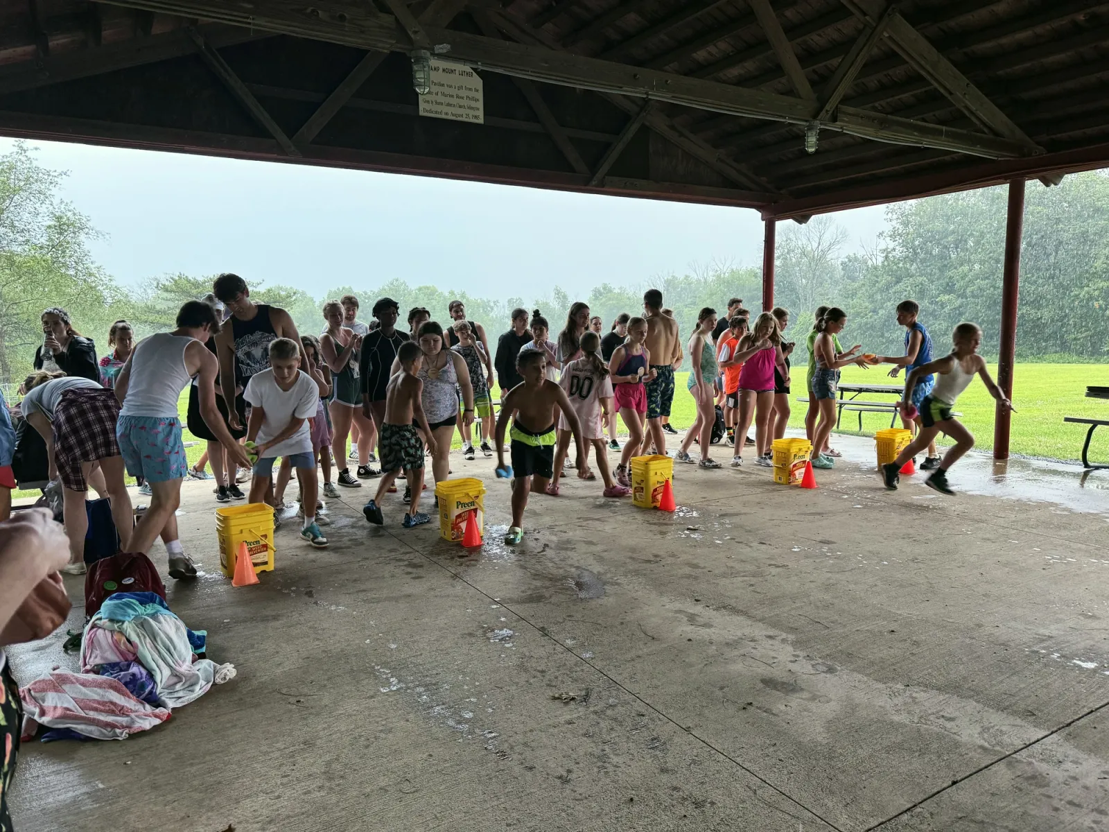 Campers run a water bucket relay race under the covered pavilion