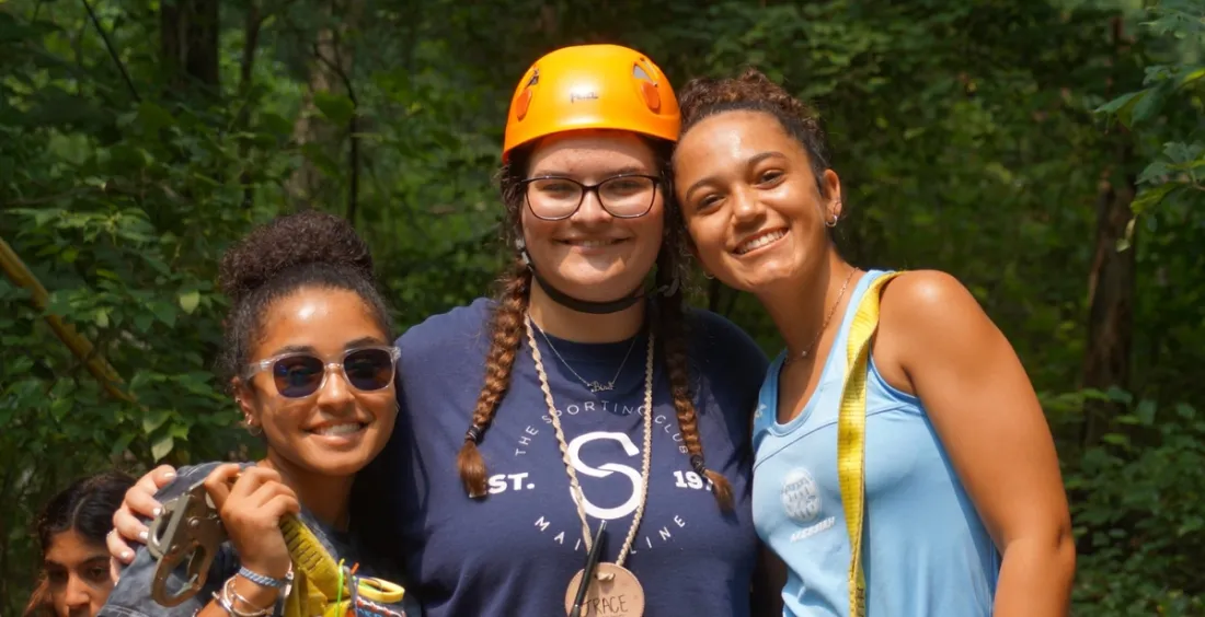 Three campers smiling in the woods
