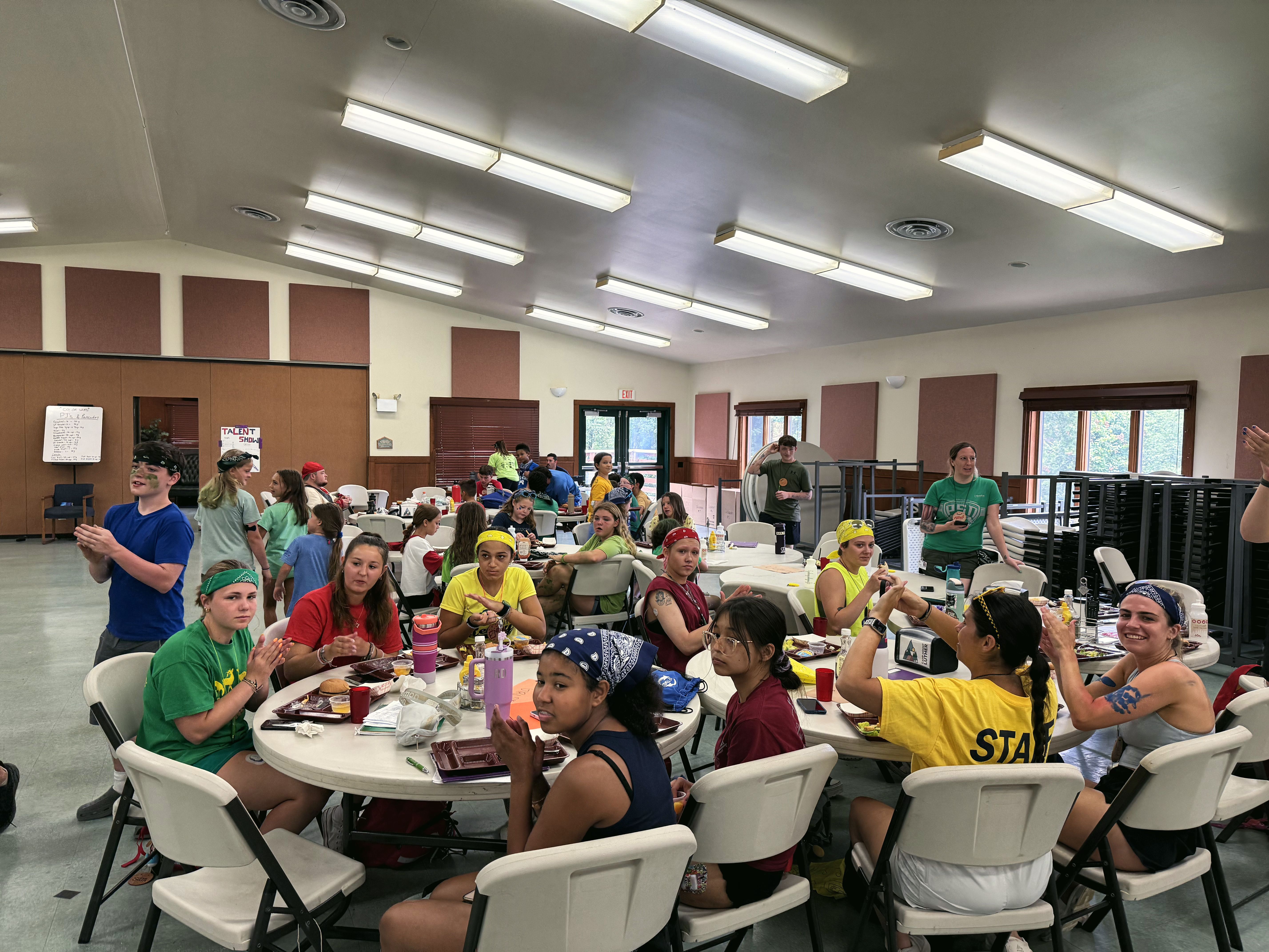 Campers share a meal at round tables in the camp dining hall.