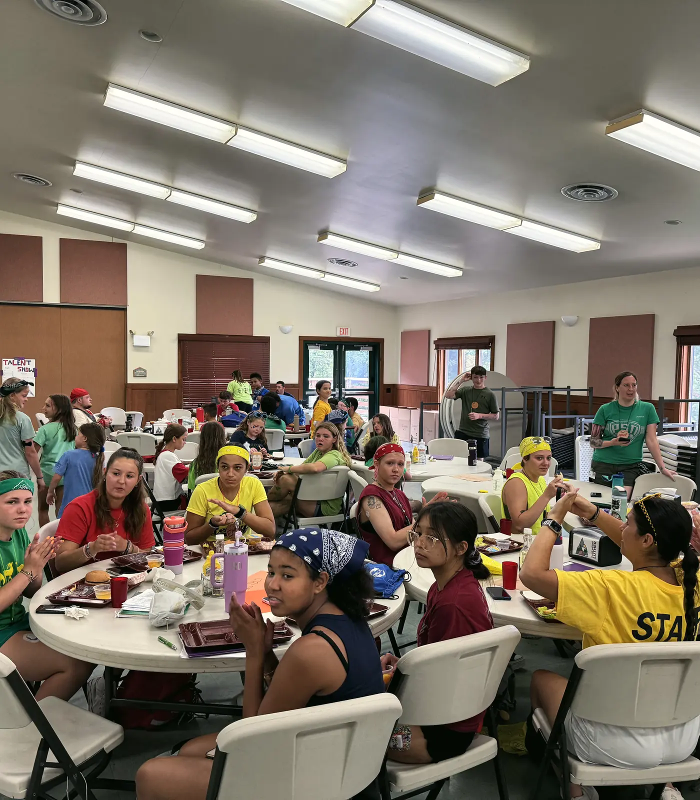 Campers share a meal at round tables in the camp dining hall.