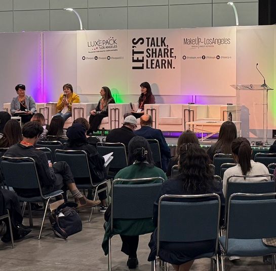 Panel discussion on stage at a LUXE PACK conference with a seated audience