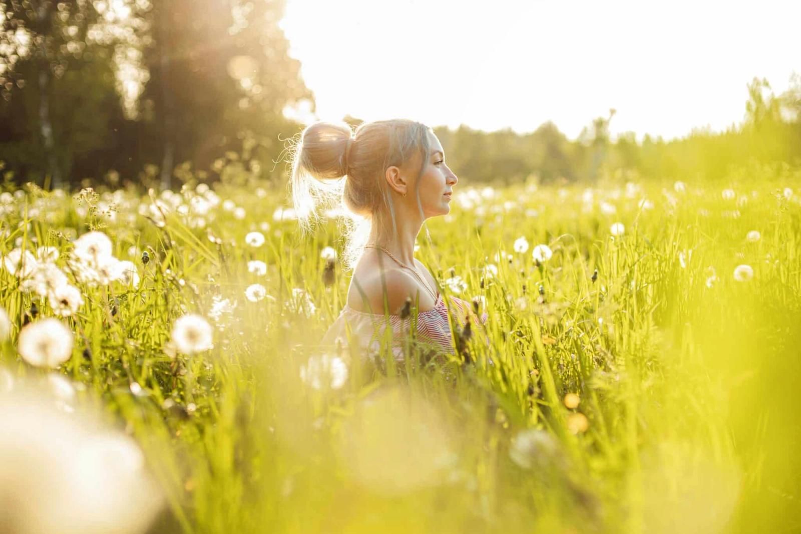 Woman sitting in a sunlit field of dandelions