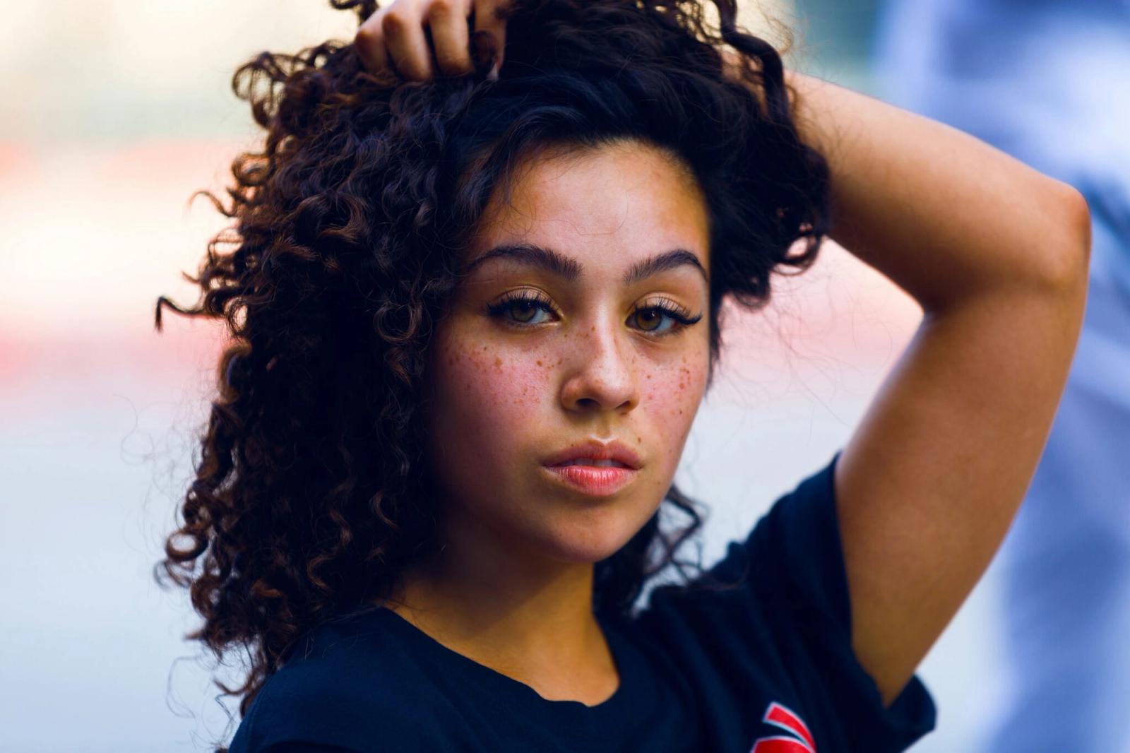 Woman with curly hair and freckles looking at the camera