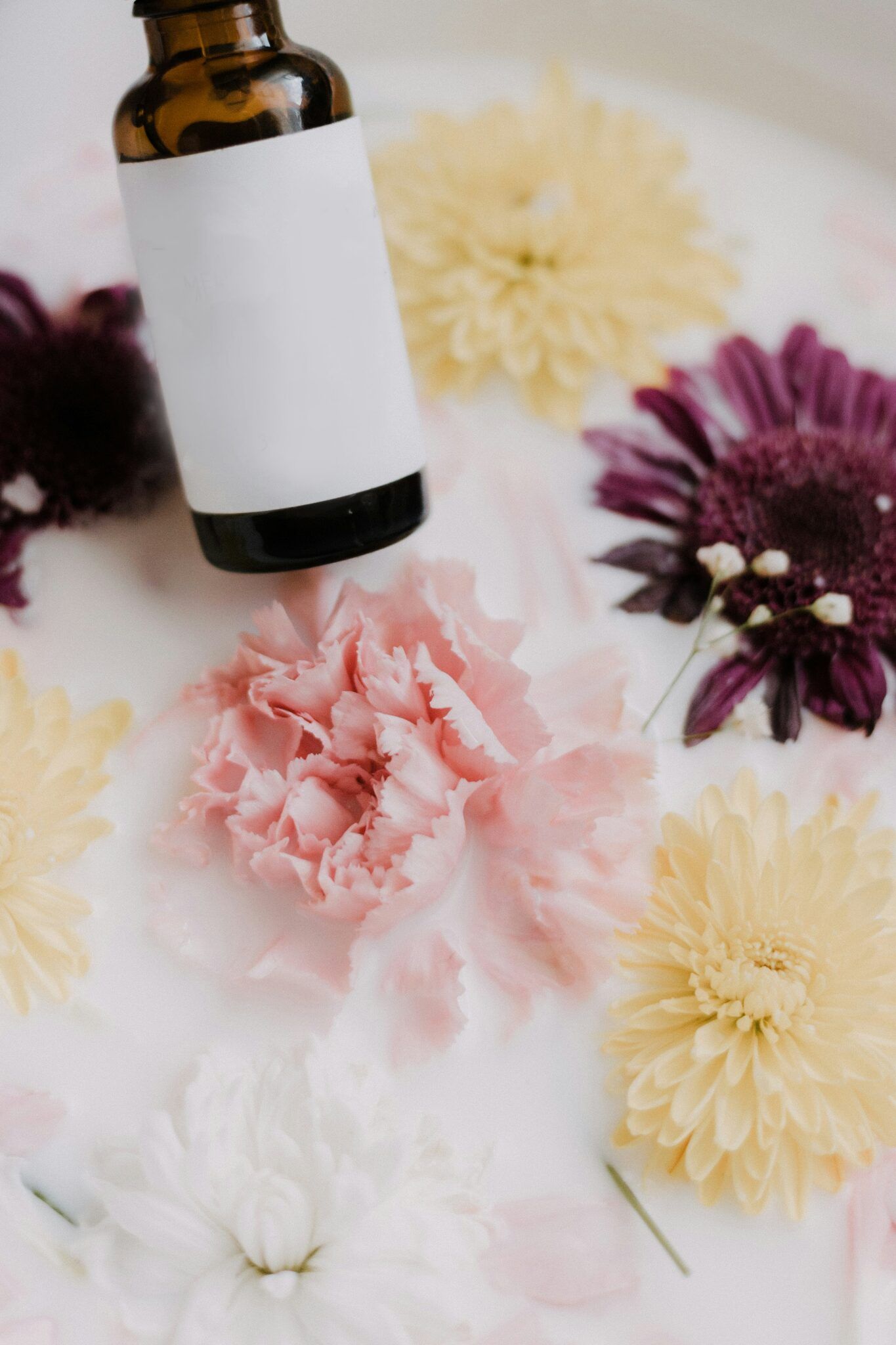 Amber glass dropper bottle lying among pink and white flowers