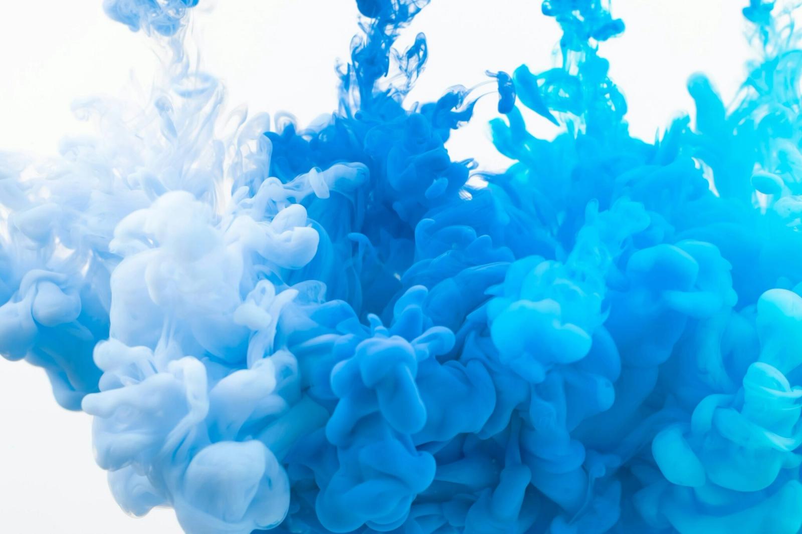 Clouds of blue ink swirling through clear water, representing printing inks