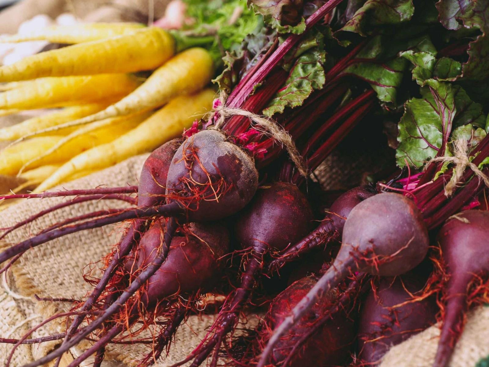 Fresh beets and yellow carrots on burlap, representing vegetable-based inks