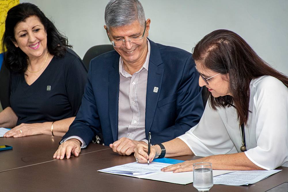 Fotografia de Cássia Turci, Roberto Medronho e Patrícia Fernandes da esquerda para direita. Fernandes assina um documento.