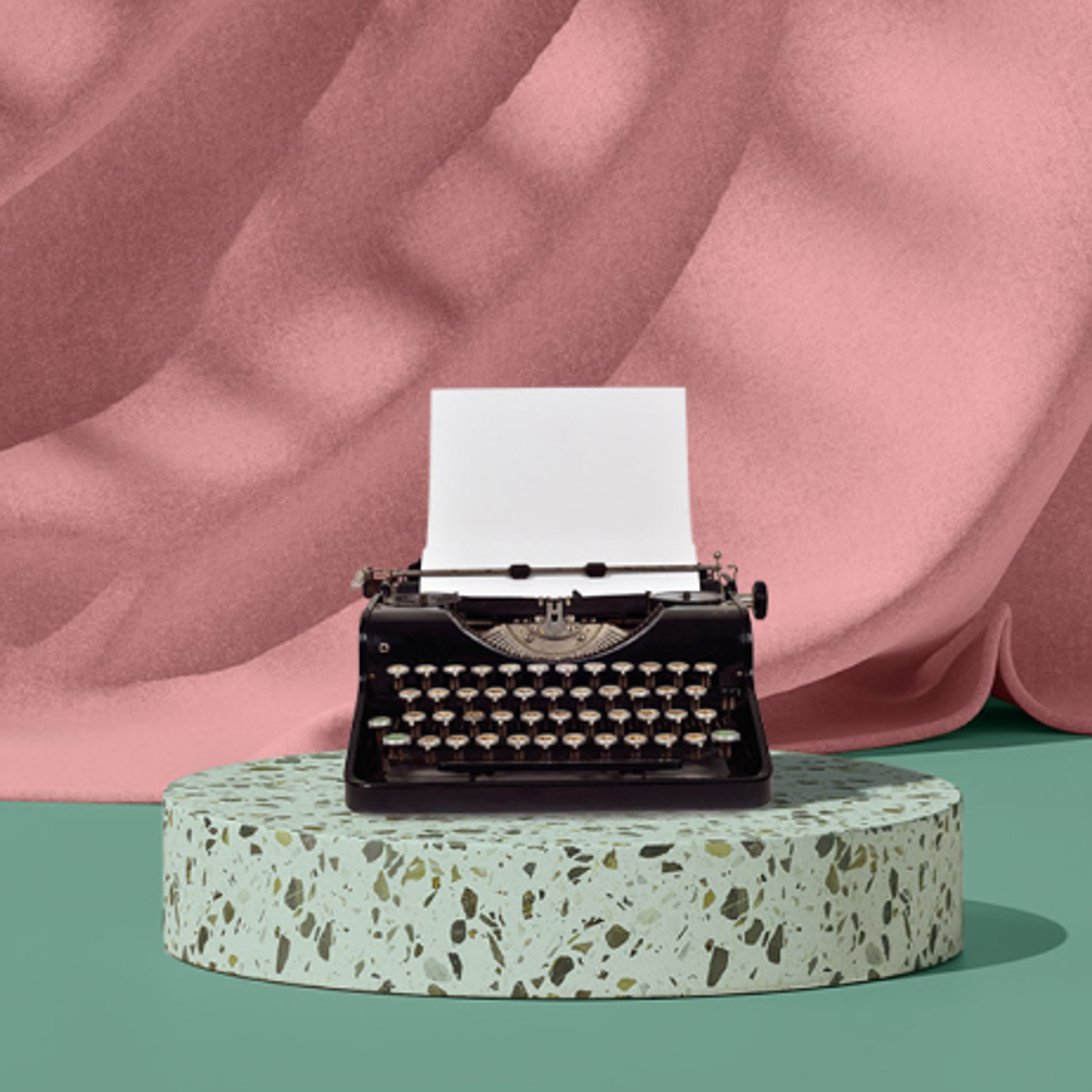Old-fashioned typewriter with paper and pink curtains in the background