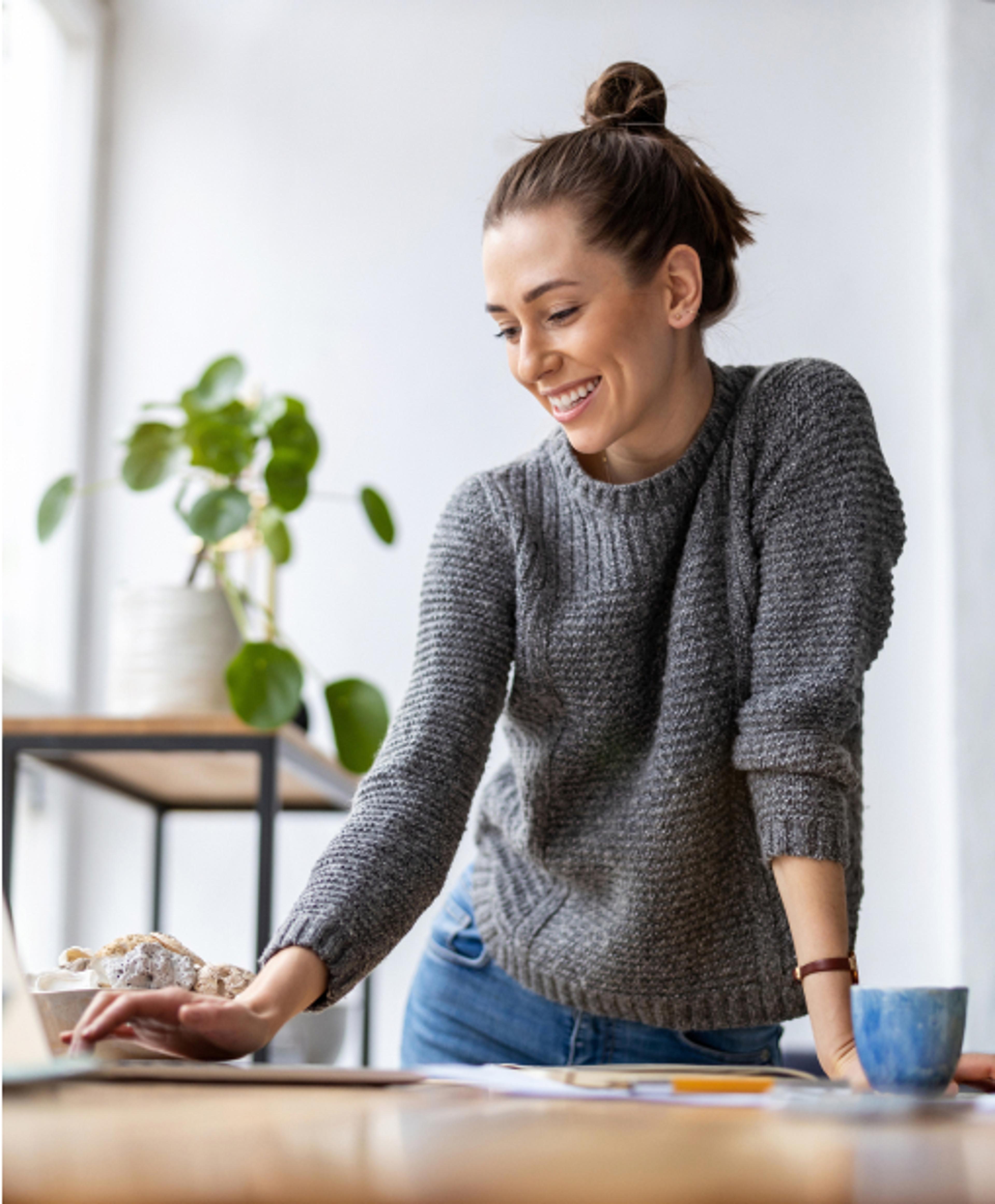 En rosa sparegris på et grønt podium. Sparegrisen har mange blomster oppi seg.