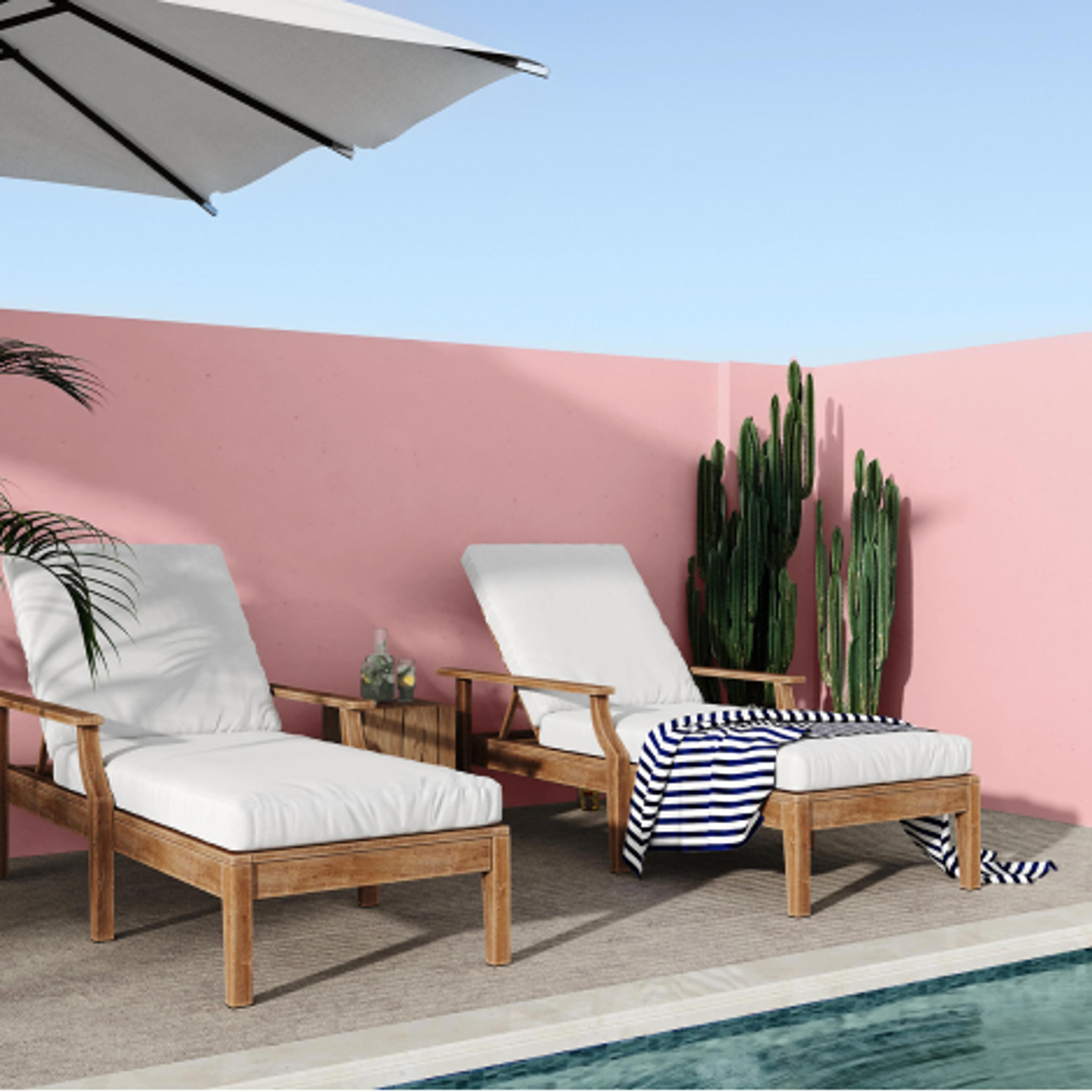 Solsenger ved basseng mot en rosa murvegg, med en kaktus i hjørnet.