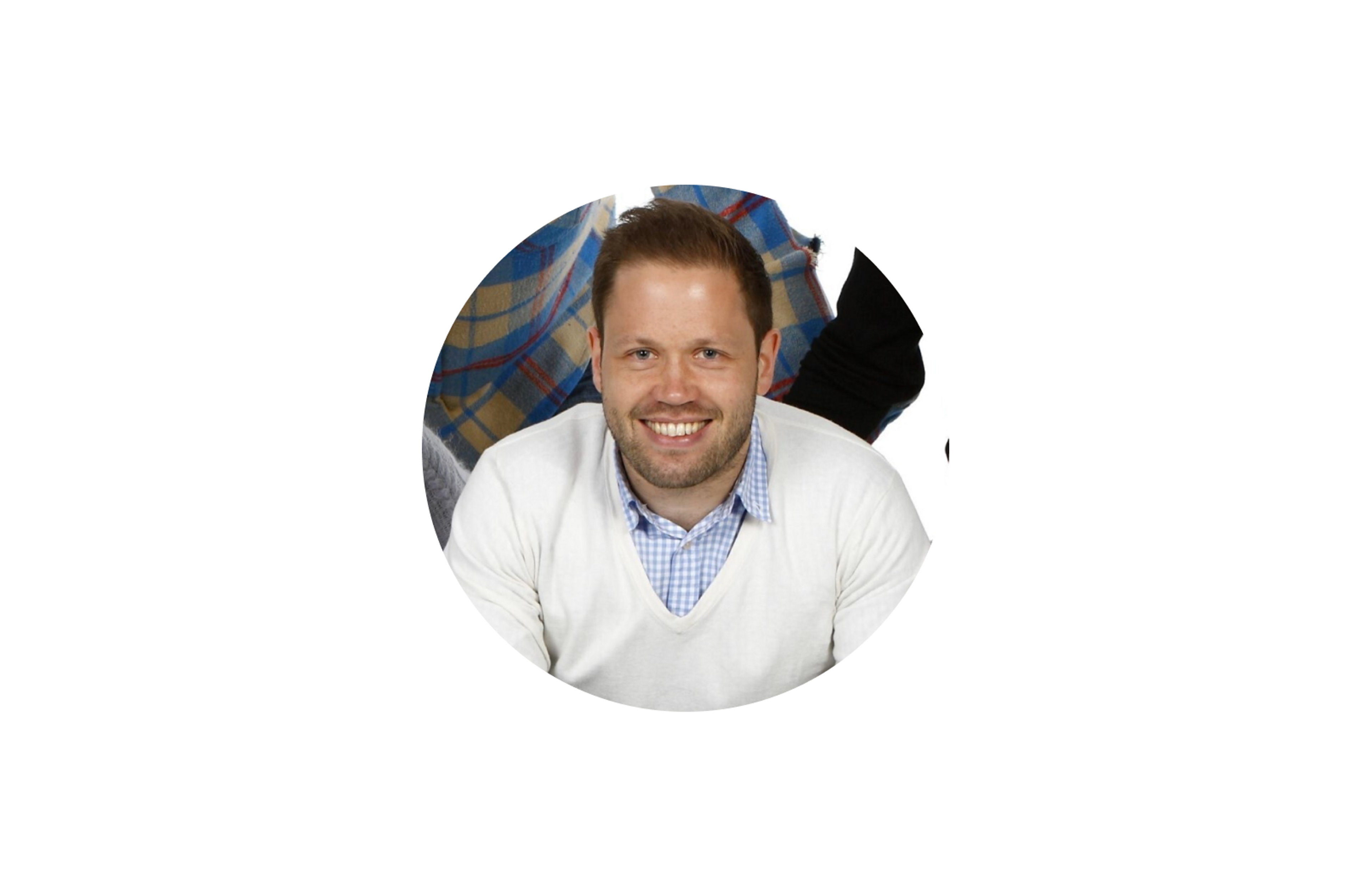 Mann med hvit genser som sitter og smiler, foto