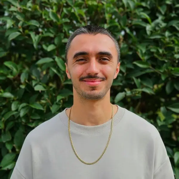 Lucian Chevallier, founder of Lumin web design, development & strategy, stood outside in front of a green leafy background.