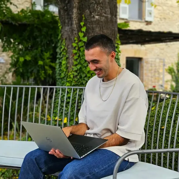 Lucian Chevallier, founder of Lumin web design and digital strategy, sat outdoors in front of a tree with his laptop.