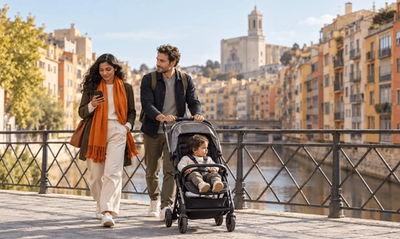 Pareja con un niño pequeño cruzando un puente del casco antiguo de Girona mientras ella lee la respuesta de su empresa sobre teletrabajar desde España con la Visa de Nómada Digital