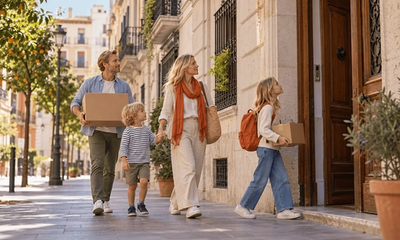 Familia británica con dos hijos llevando cajas de mudanza a su nueva casa en una calle tranquila de Valencia, España, el día de su mudanza desde el Reino Unido
