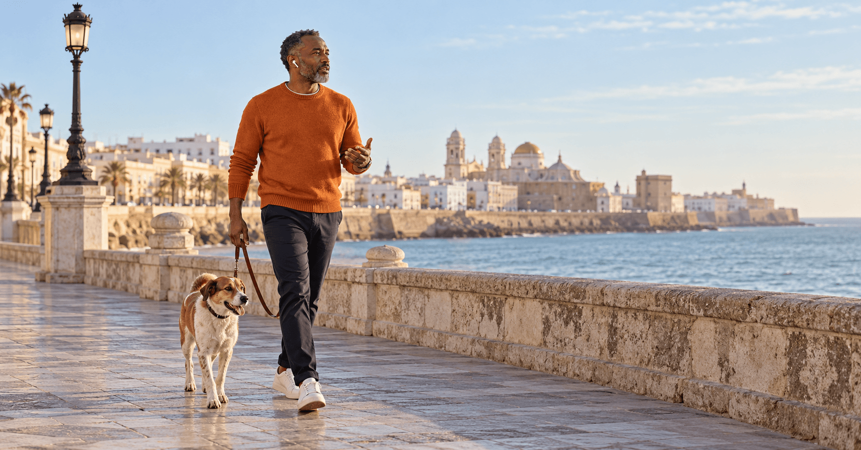 Propietario de una empresa de EE. UU. paseando a su perro por el paseo marítimo de Cádiz mientras habla con su equipo, dirigiendo su LLC desde España con la Visa de Nómada Digital