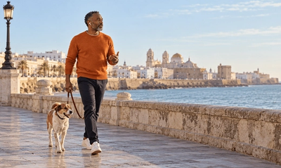Propietario de una empresa de EE. UU. paseando a su perro por el paseo marítimo de Cádiz mientras habla con su equipo, dirigiendo su LLC desde España con la Visa de Nómada Digital