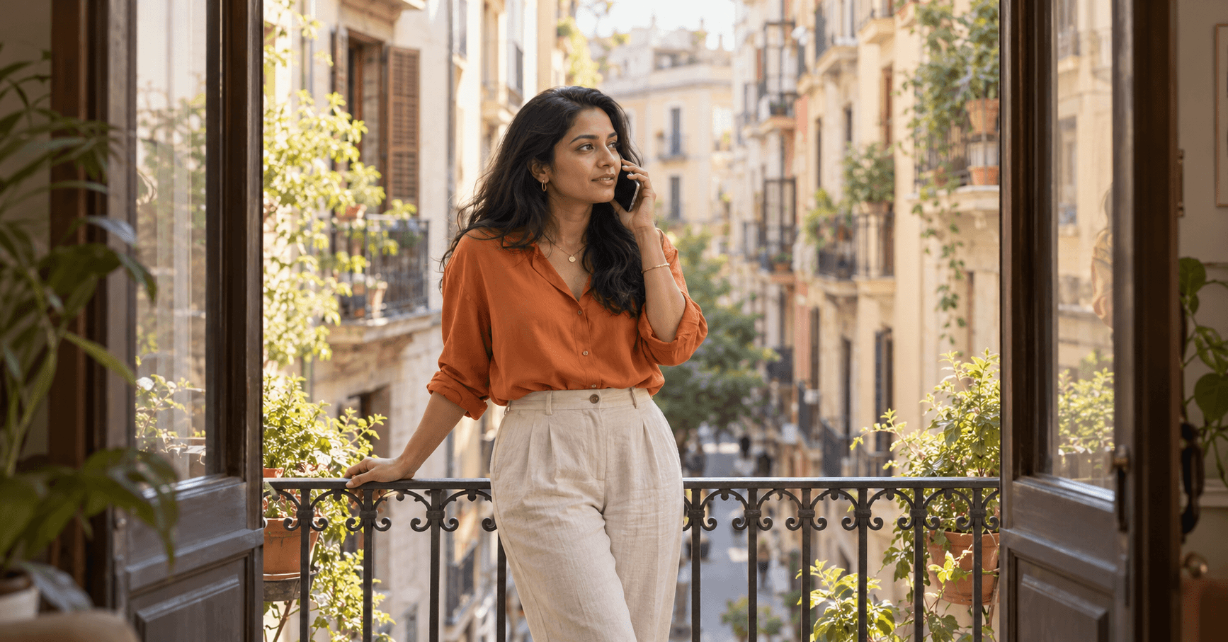 Mujer atendiendo una llamada en el balcón de su piso en el barrio de Gràcia, en Barcelona, hablando de la carta del empleador para su Visa de Nómada Digital de España